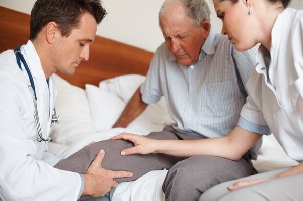 Doctor care examinează genunchiul pacientului